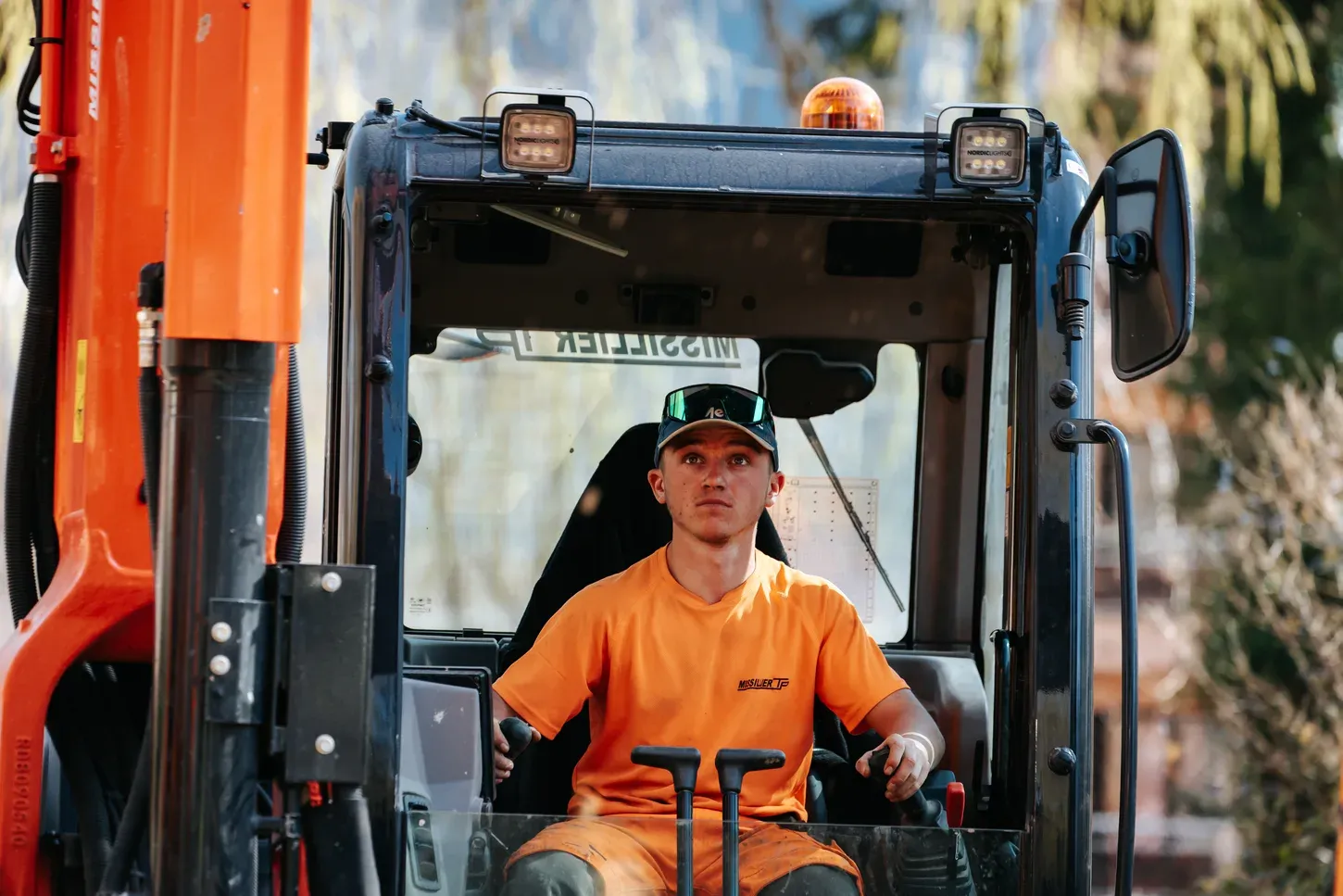 Chauffeur Missillier TP aux commandes dans la cabine équipée d'un engin de chantier récent